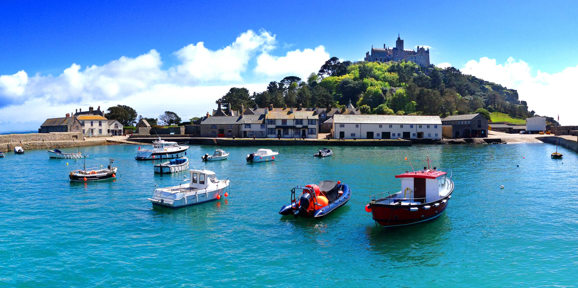 Picturesque harbour with boats on turquoise water and St Michael’s Mount rising in the background, near Praa Sands Holiday Park.