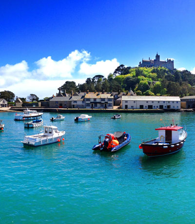Picturesque harbour with boats on turquoise water and St Michael’s Mount rising in the background, near Praa Sands Holiday Park.