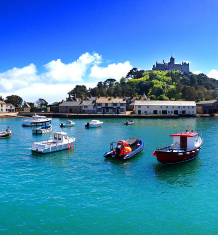 Picturesque harbour with boats on turquoise water and St Michael’s Mount rising in the background, near Praa Sands Holiday Park.