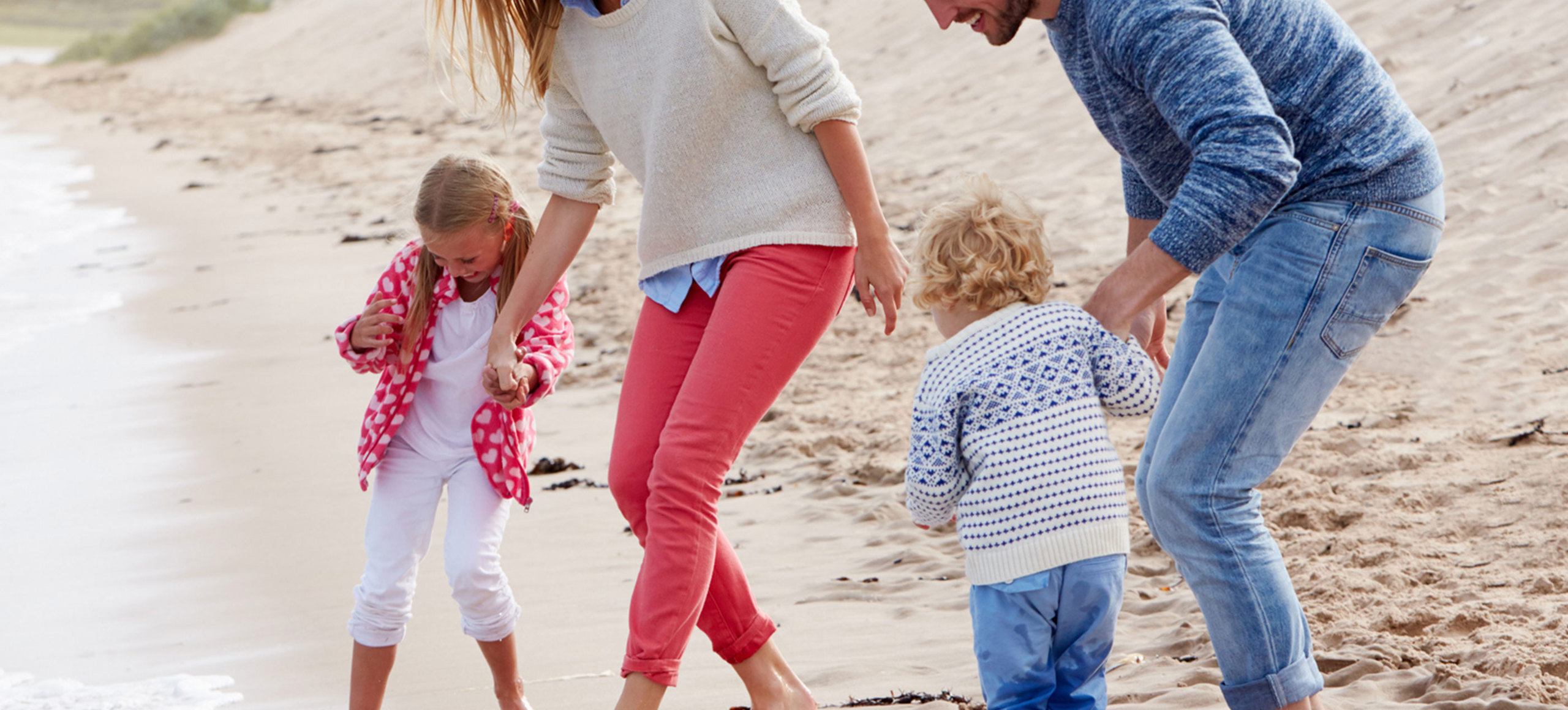Parents and children playing at the shoreline at a sandy beach near Praa Sands Holiday Park.