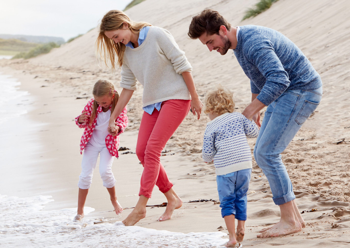 Parents and children playing at the shoreline at a sandy beach near Praa Sands Holiday Park.