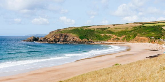 Golden sandy shoreline of Praa Sands beach with blue sea near Praa Sand Holiday Park