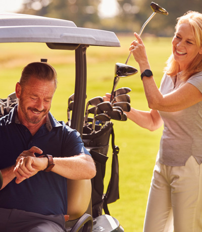 Lady selecting golf club from buggy with husband sitting in the passenger seat