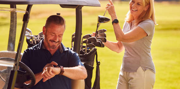 Lady selecting golf club from buggy with husband sitting in the passenger seat