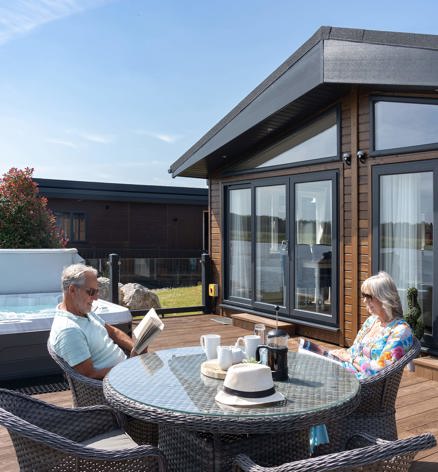 Delamere Couple Sat Outside Relaxing By Lake