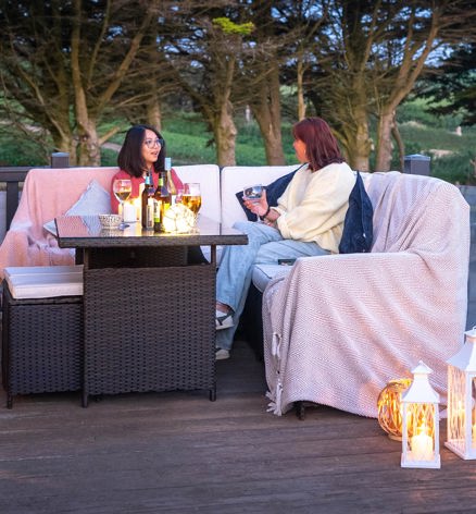 Friends relaxing On Holiday Home Decking With Drink