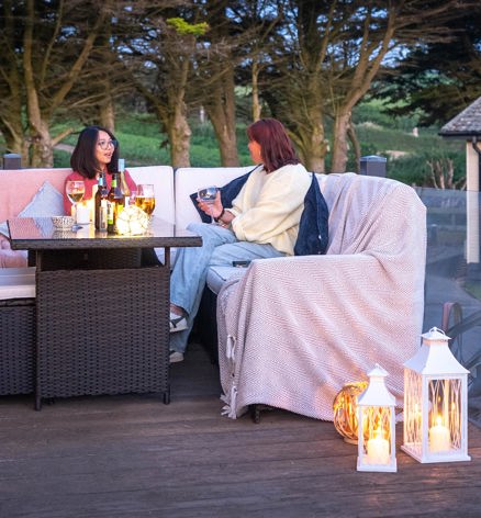 Friends relaxing On Holiday Home Decking With Drink