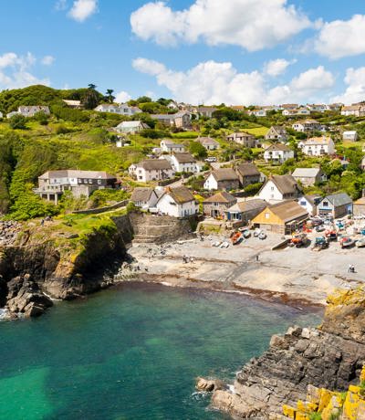 Colourful fishing village of Cadgwith Cove with traditional cottages and rugged cliffs, near Praa Sands Holiday Park.