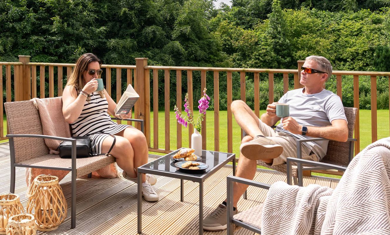 Couple Relaxing On Dartmoor Holiday Home Decking