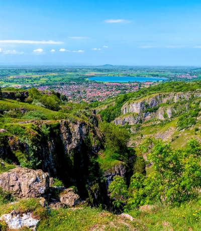Panoramic daytime view of Cheddar Gorge with rocky cliffs and green countryside stretching into the distance, Near Brokerswood Holiday Park.