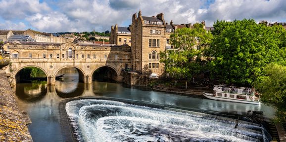 Iconic Pulteney Bridge in Bath with cascading weir and riverboat on the River Avon, Near Brokerswood Holiday Park.
