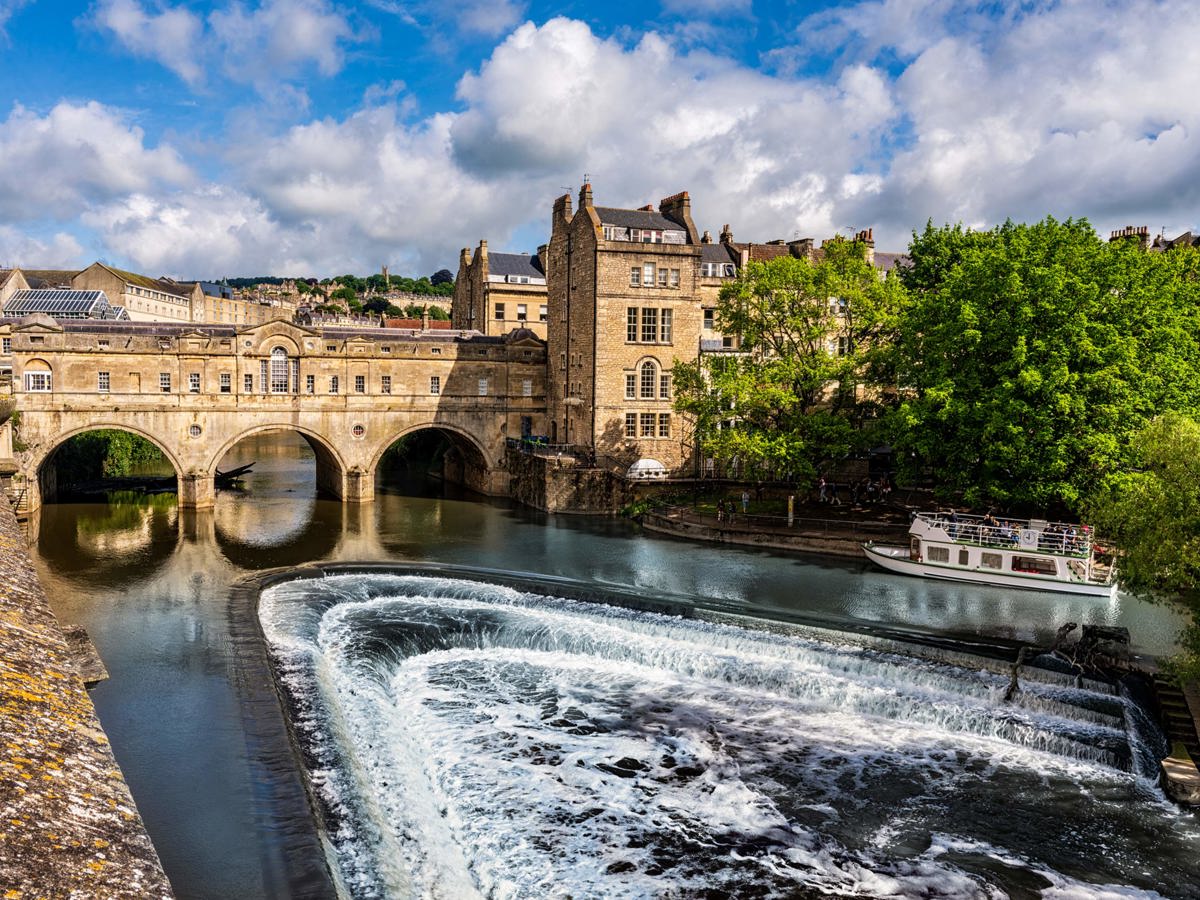 Iconic Pulteney Bridge in Bath with cascading weir and riverboat on the River Avon, Near Brokerswood Holiday Park.