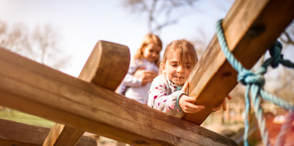 Children climbing and playing on a wooden playground structure outdoors, Near Brokerswood Holiday Park.
