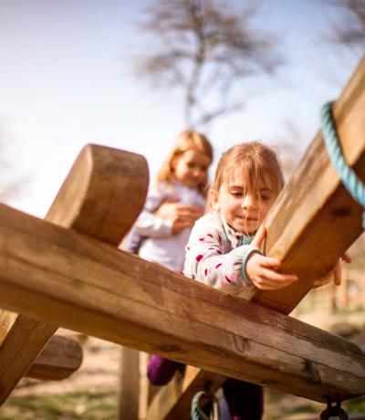 Children climbing and playing on a wooden playground structure outdoors, Near Brokerswood Holiday Park.