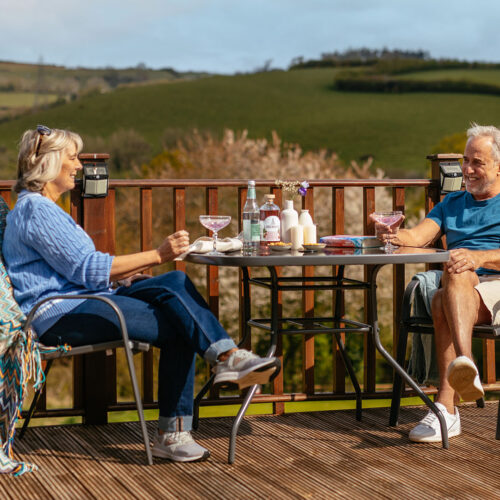 Couple enjoying cocktails out on the deck overlooking the Devon hill