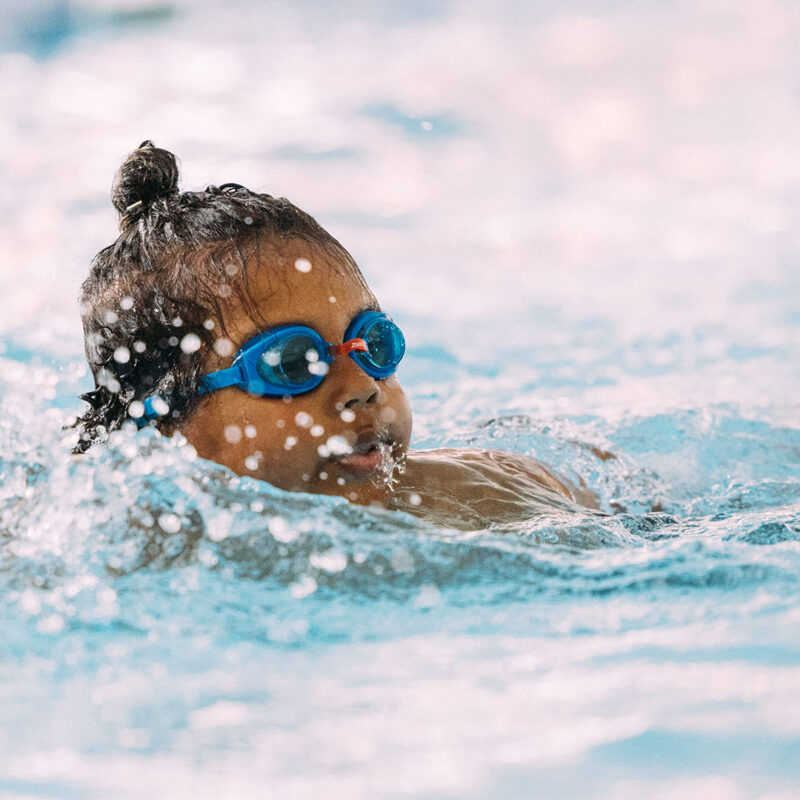 Child swimming in pool with goggles on