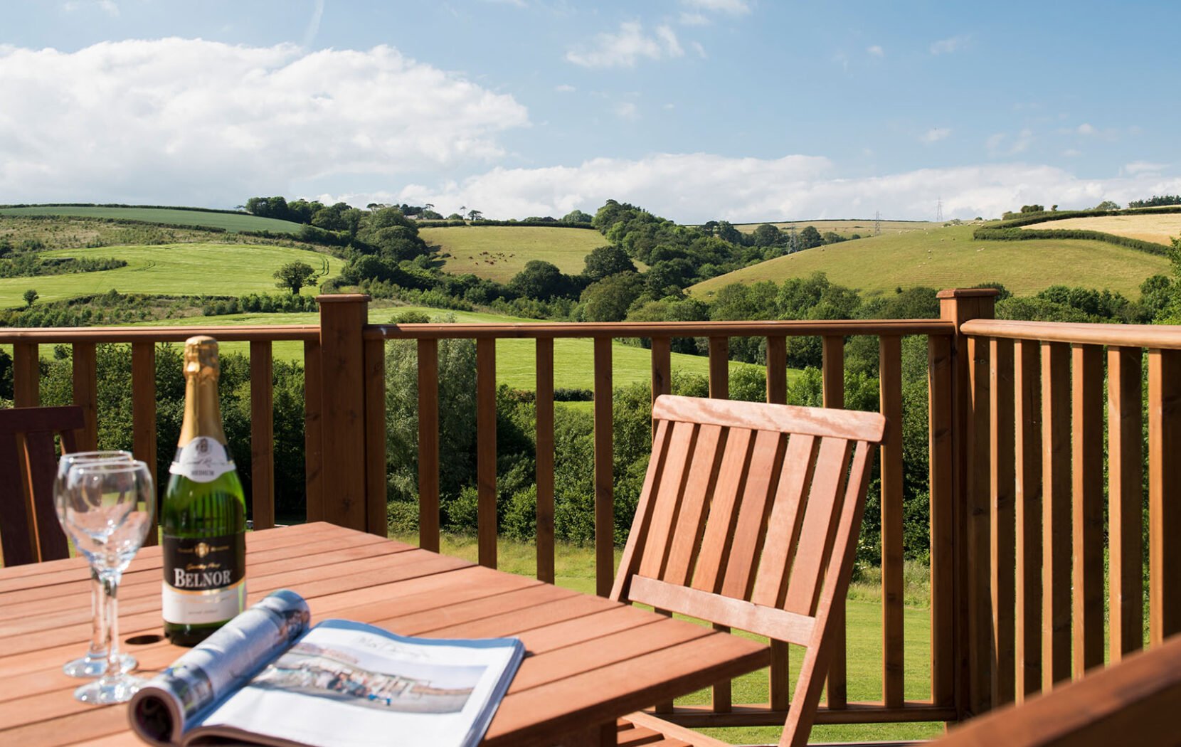 Wine glasses on a table, on a deck overlooking the Devon hills