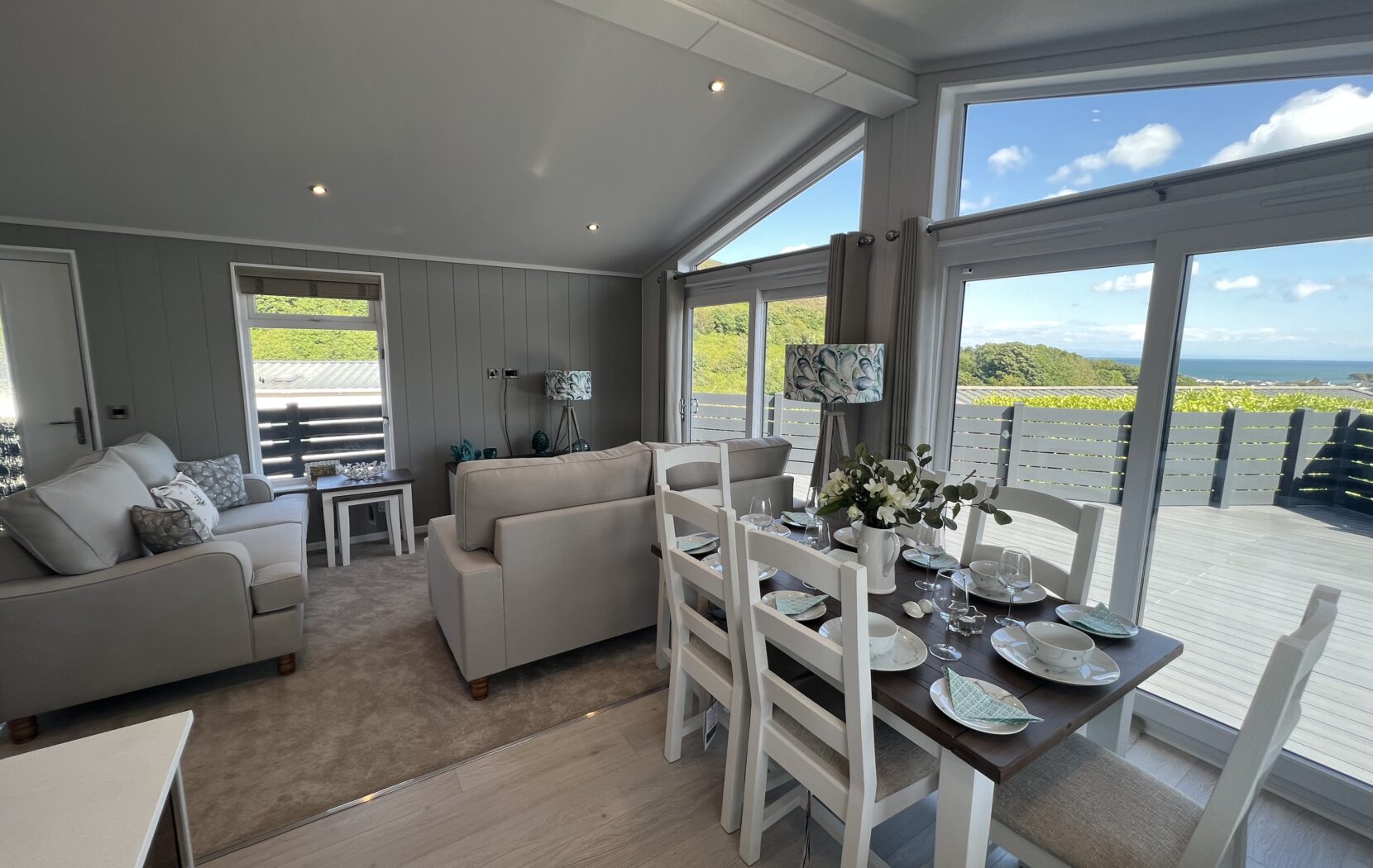 Open plan kitchen diner and living area, with large glass sliding doors leading to a spacious sundeck with seaviews