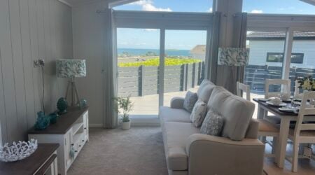 Behind a large sofa you can see two large sliding doors leading out onto a spacious sundeck with seaviews