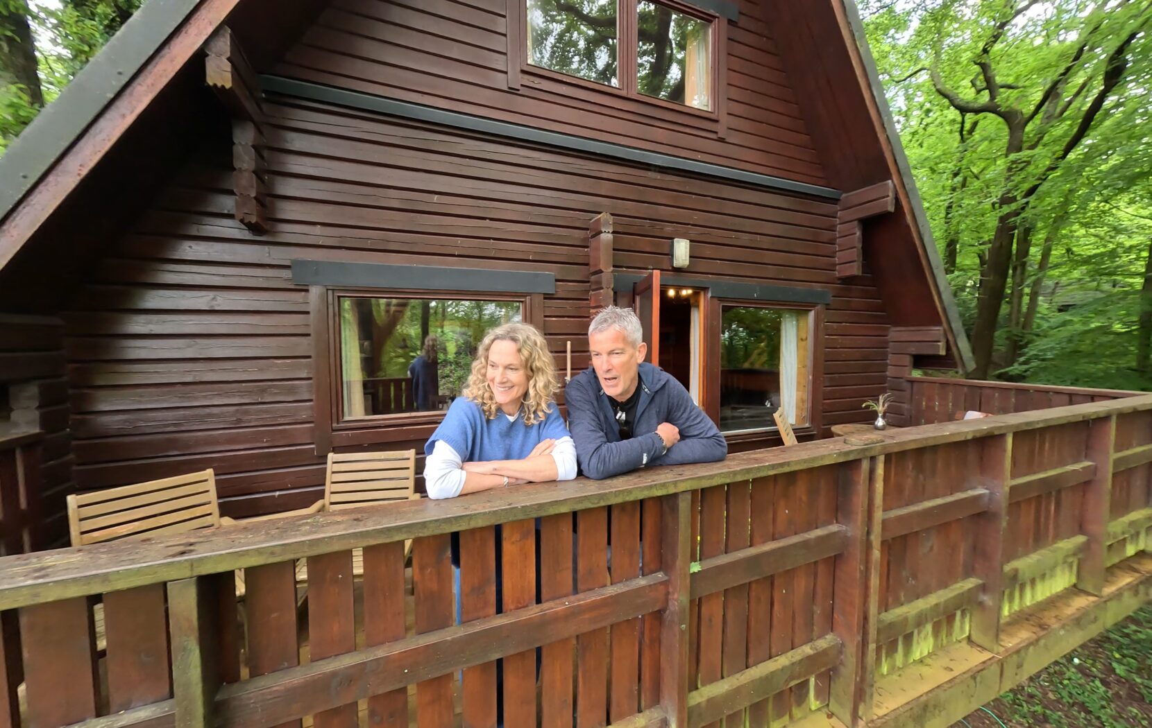 A-frame woodland lodge with couple looking out on the decking area.