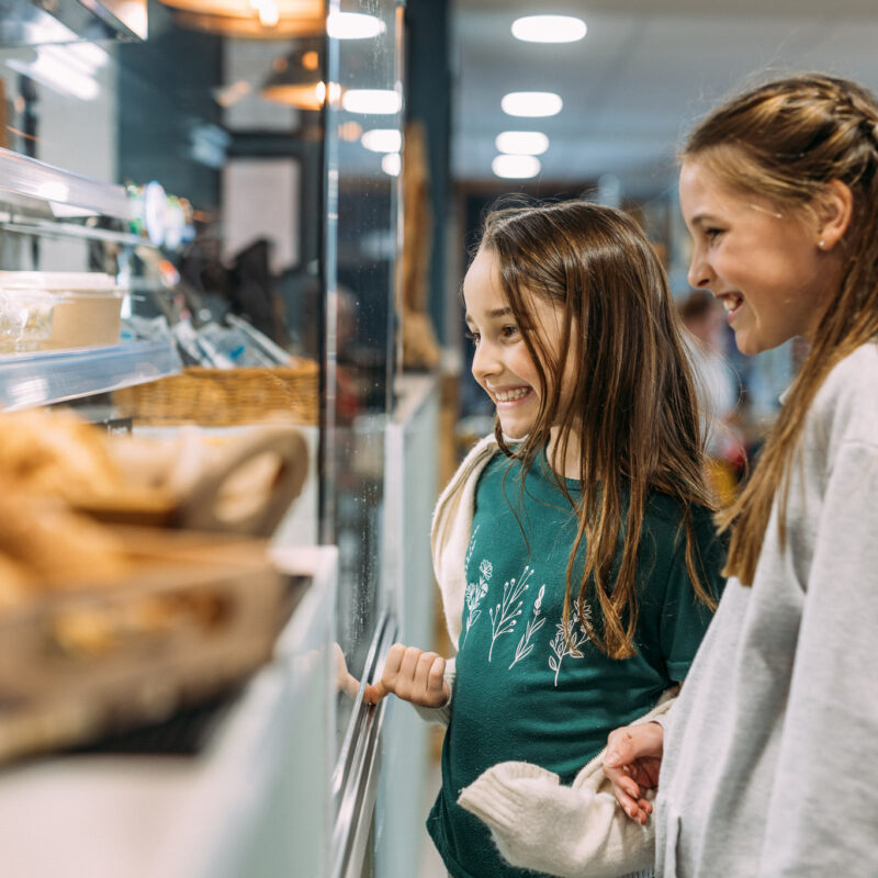 Two girls smiling while looking at a selection of food to buy at The Hive Cafe